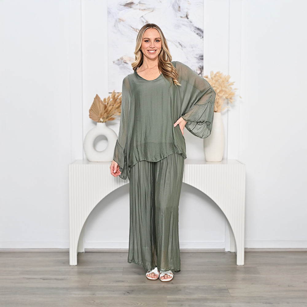 Woman wearing a green outfit standing in a room with decorative elements.