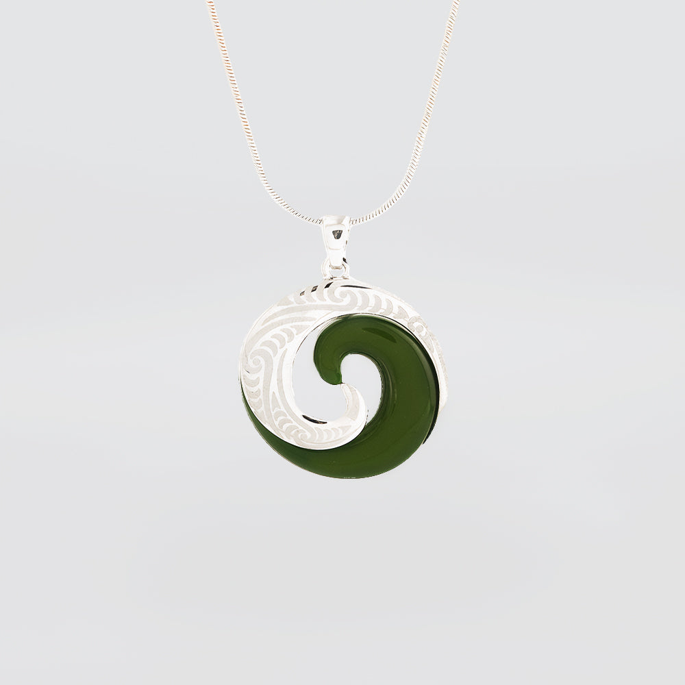 Green jade pendant with silver swirl design on a light gray background